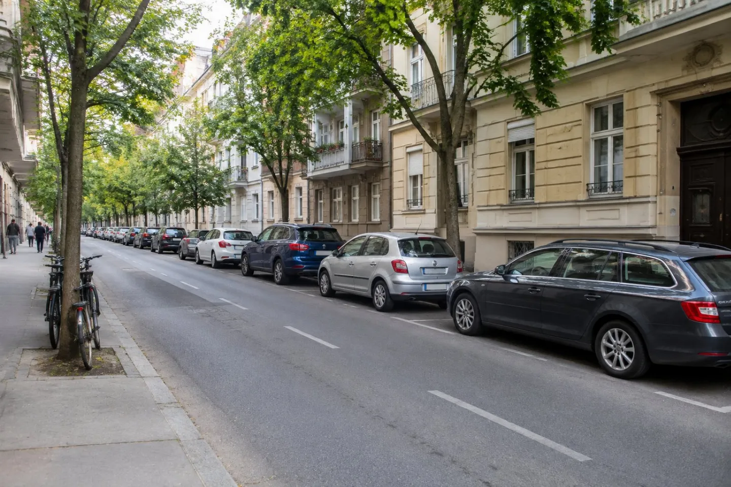 Cars parked along a city street beside residential buildings.